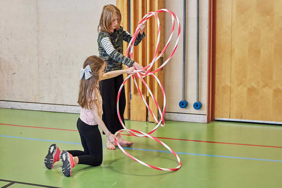 Kinder spielen mit Hula-Hoop-Reifen in der Schulturnhalle