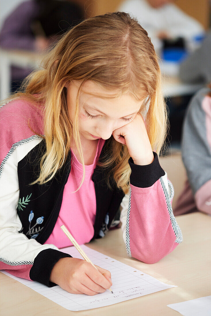 Mädchen, das in der Schule eine Schreibaufgabe erledigt