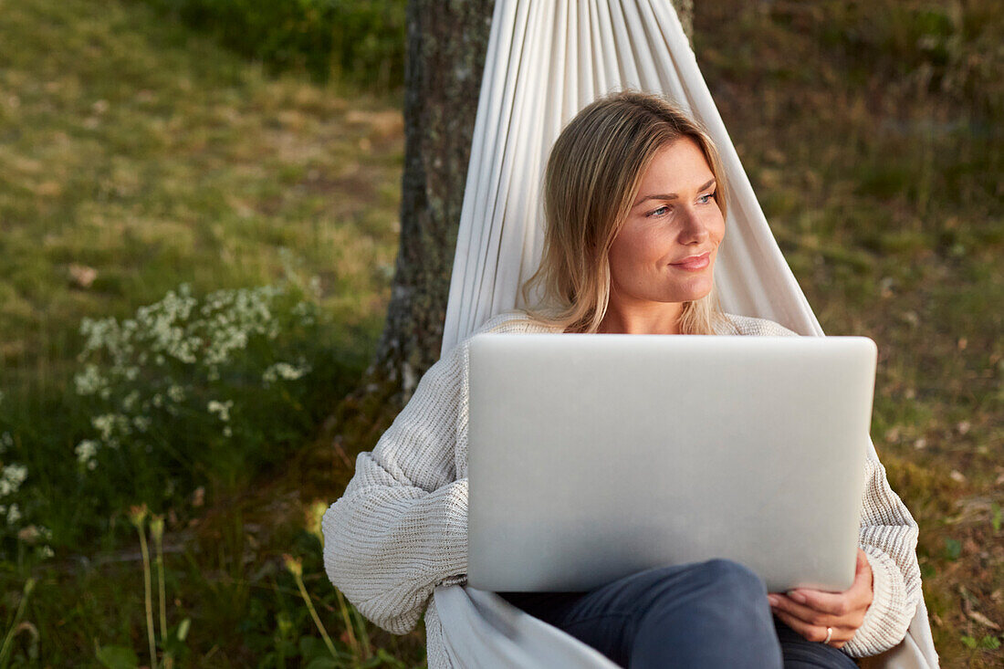 Woman using laptop on hammock