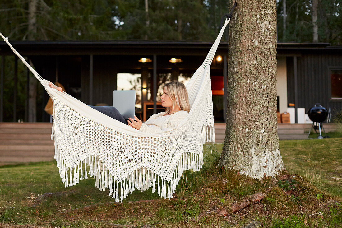 Woman using laptop on hammock