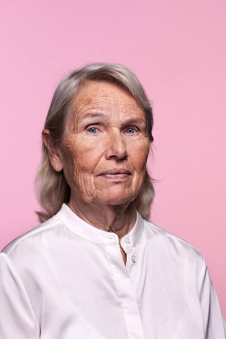 Portrait of senior woman against pink background