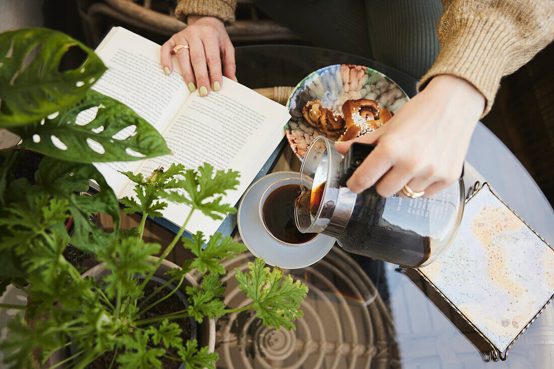 Frau liest ein Buch und trinkt Tee und isst einen Snack