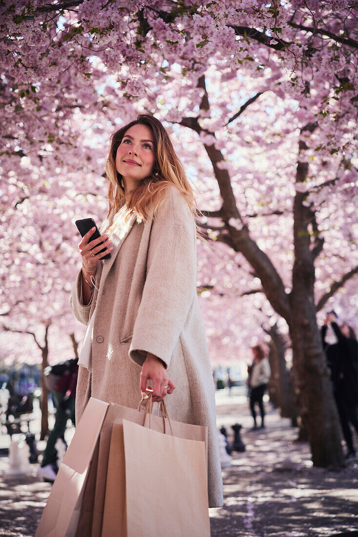 Young woman standing under cherry blossom