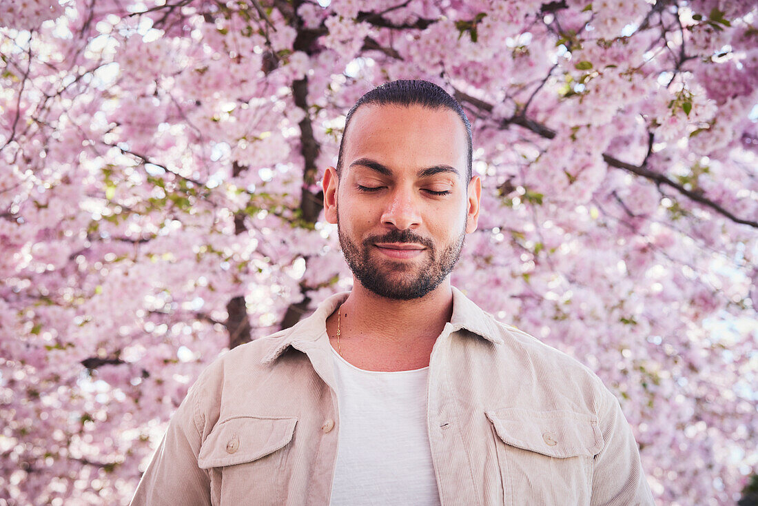 Young man standing under cherry blossom
