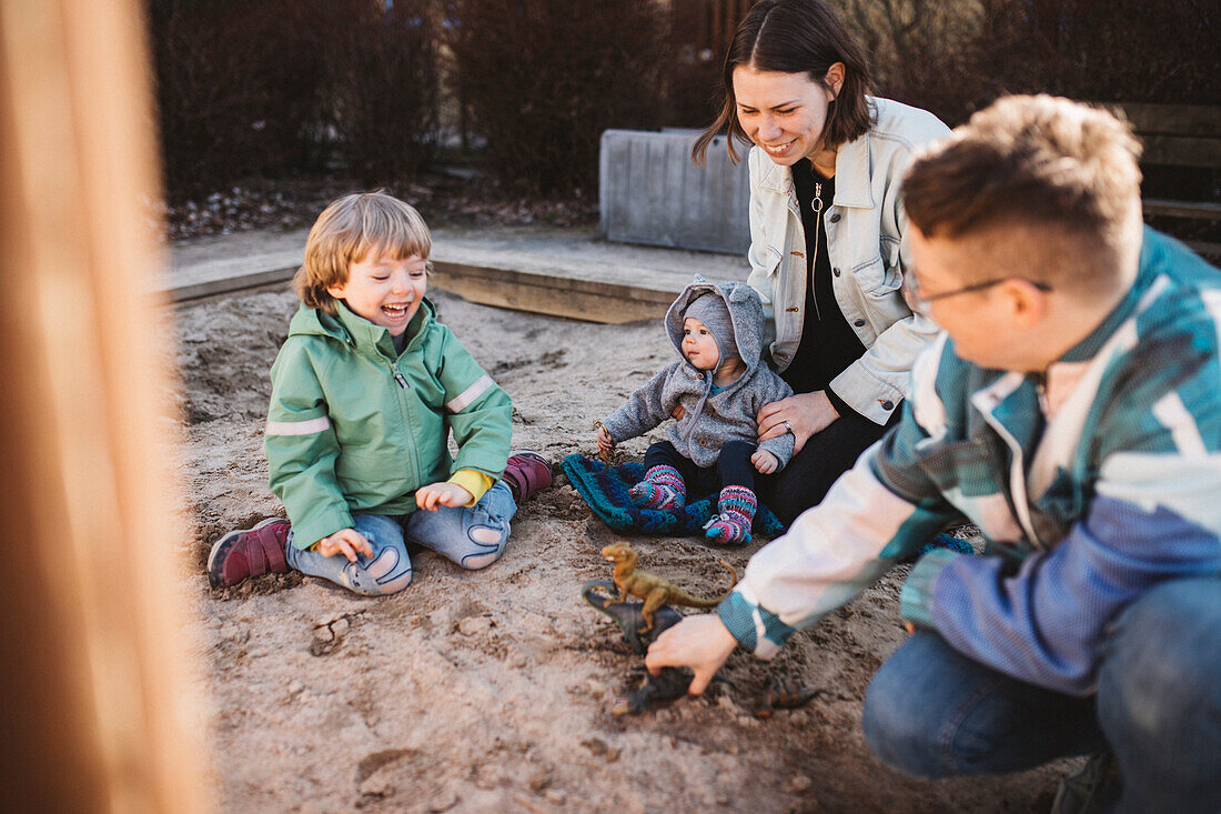 Familie mit Kindern beim Spielen im Sandkasten