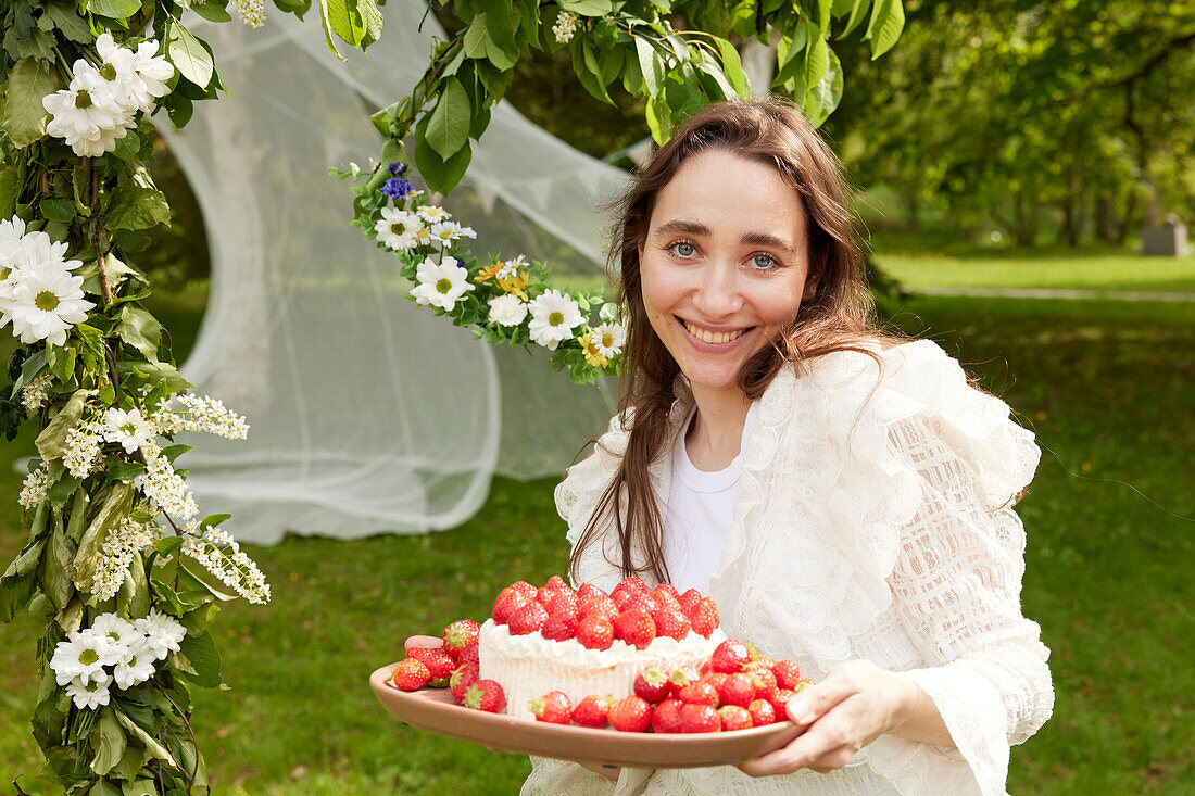 Portrait of woman carrying cake outdoors