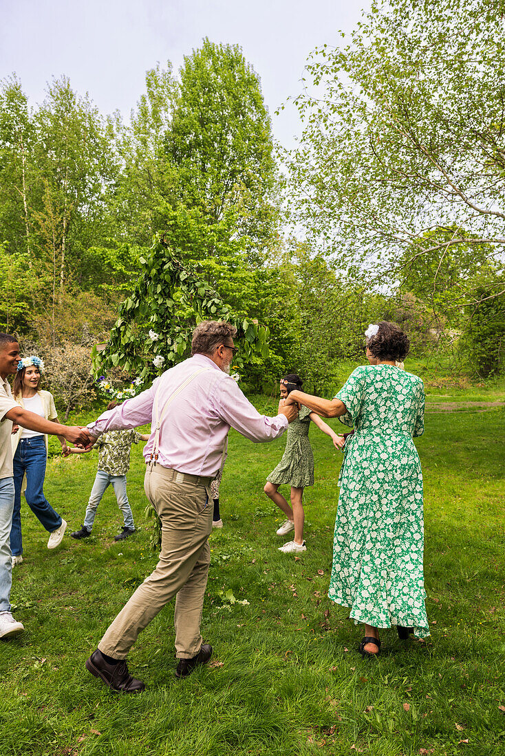 Menschen tanzen um den Mittsommer-Maibaum