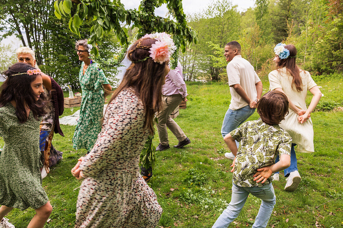 Menschen tanzen um den Mittsommer-Maibaum