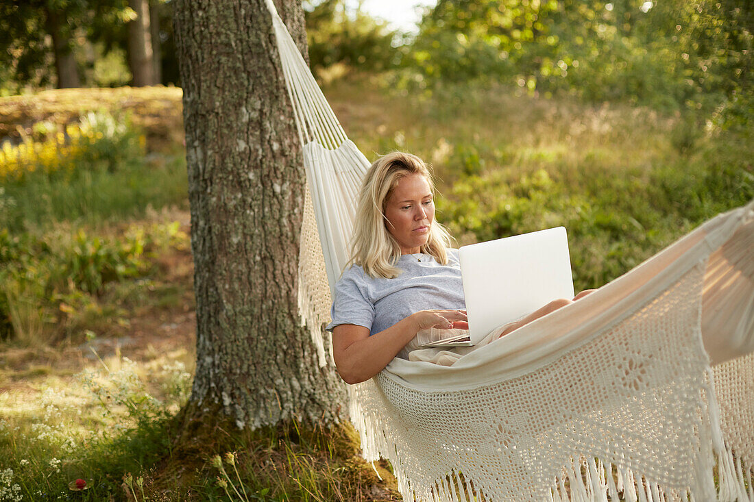 Woman using laptop in hammock