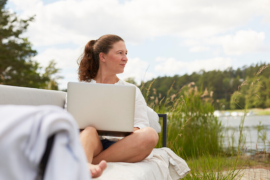 Woman using laptop on garden bench
