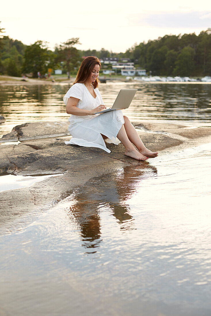 Woman using laptop at lake