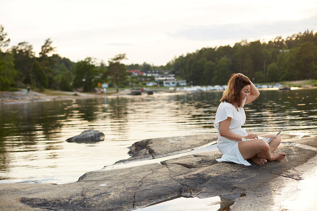 Woman using laptop at lake