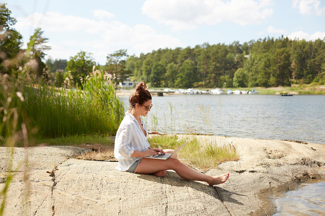 Woman using laptop at lake