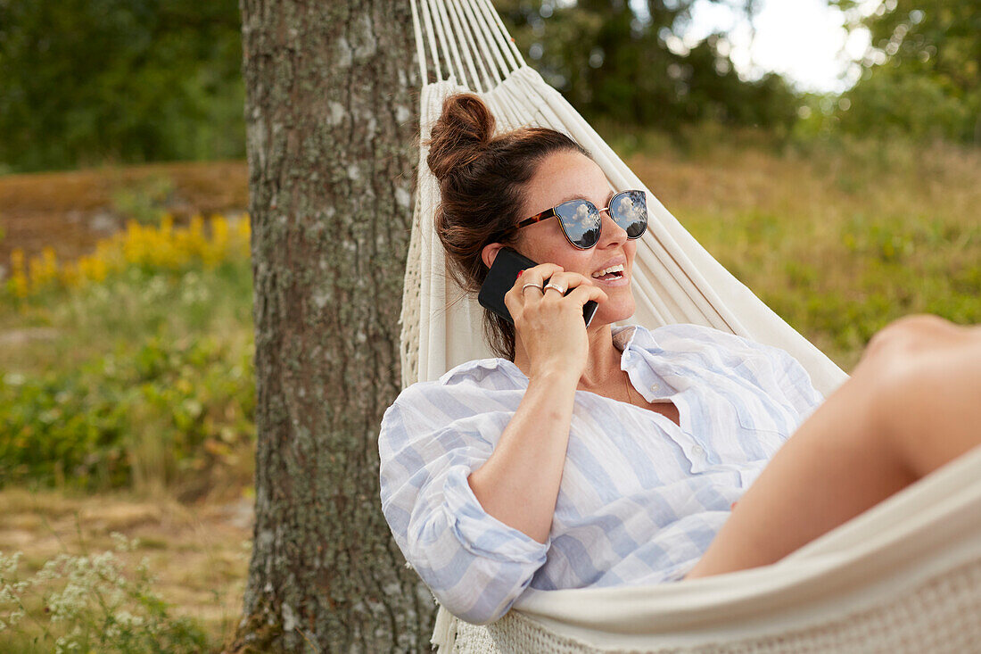 Woman using phone on hammock