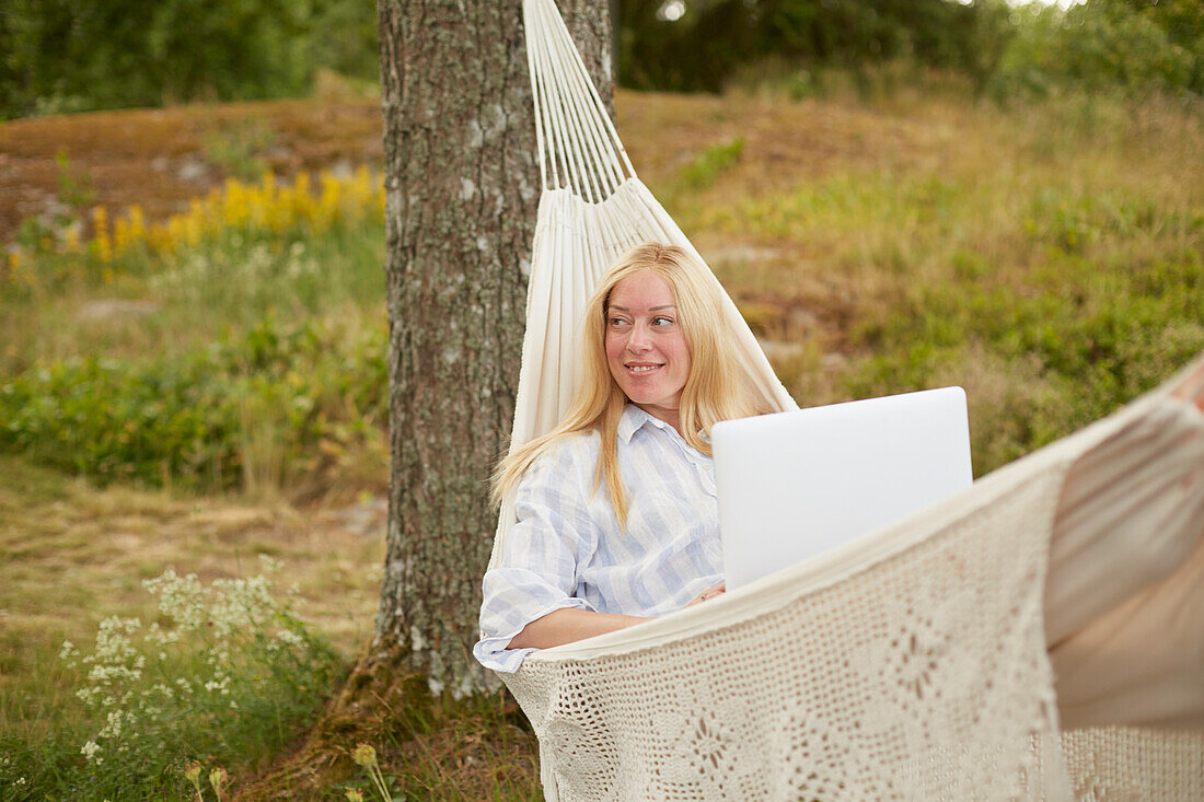 Woman using laptop on hammock