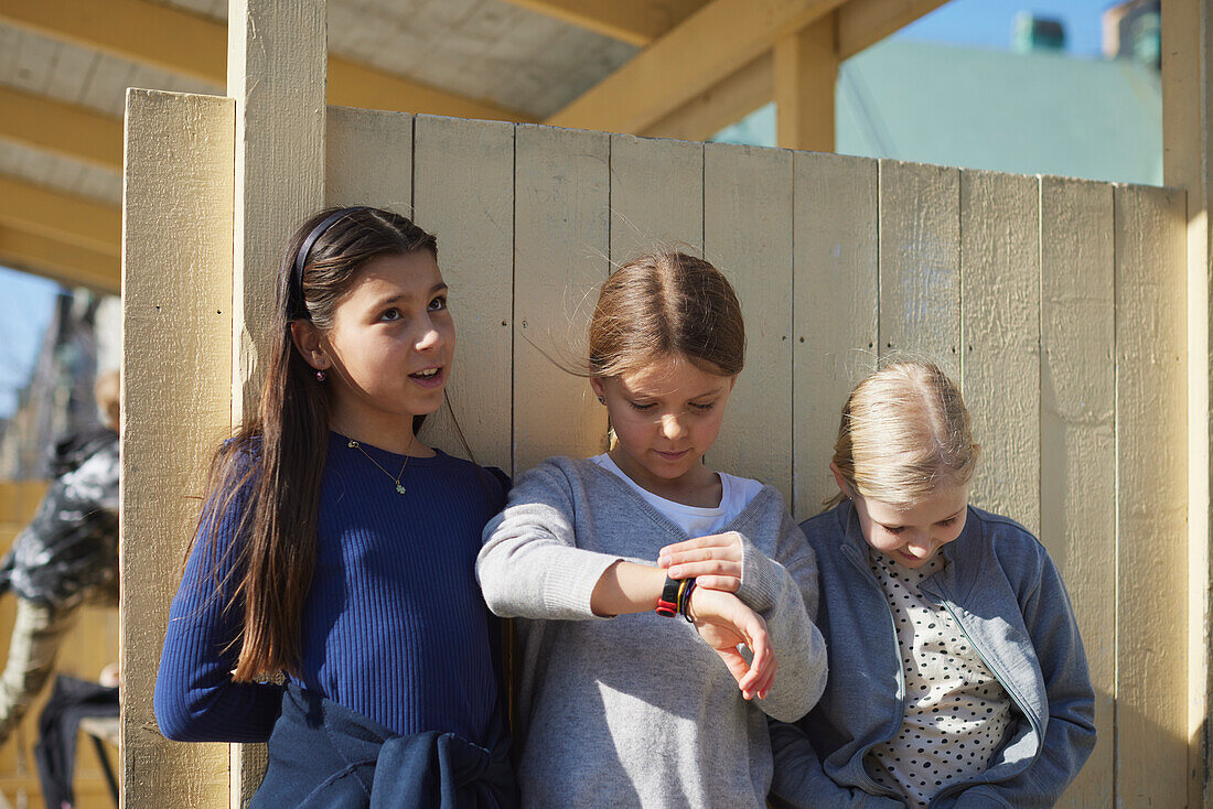 Girls standing against wooden wall