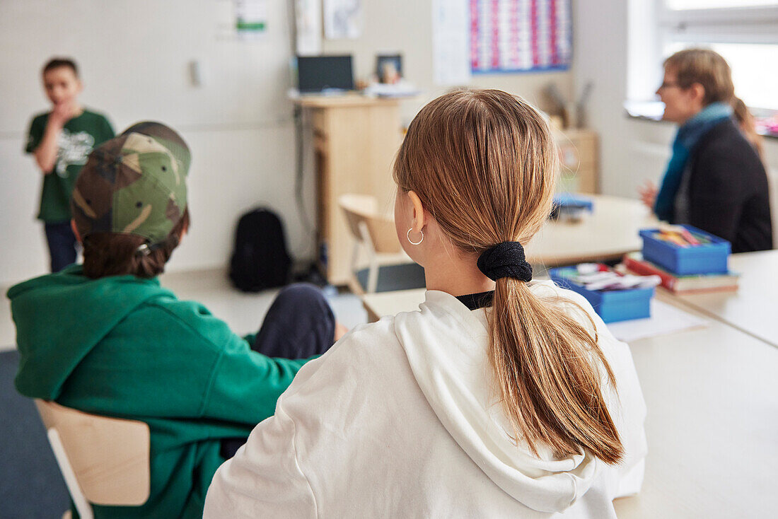 Rear view of girl sitting in classroom