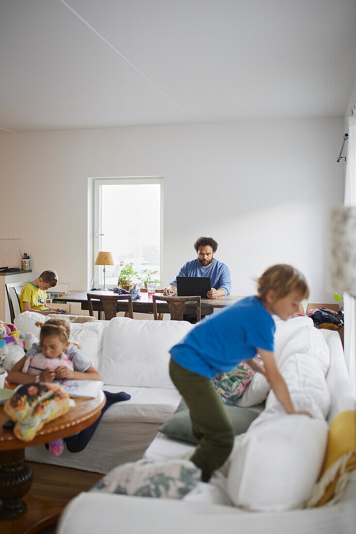 Kinder spielen, während der Vater von zu Hause aus arbeitet