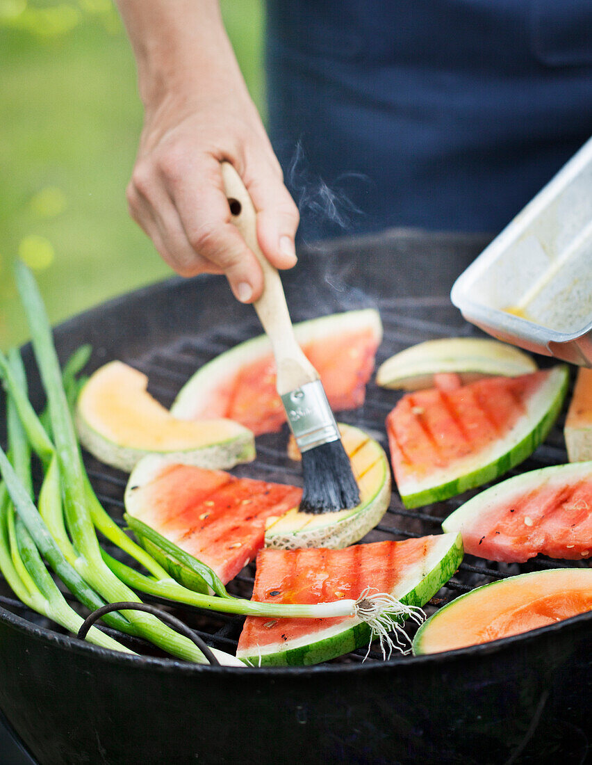 Women preparing watermelon on barbecue