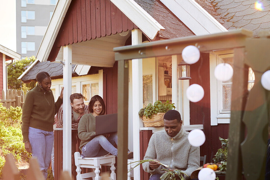 Group of friends with laptop in front of wooden house