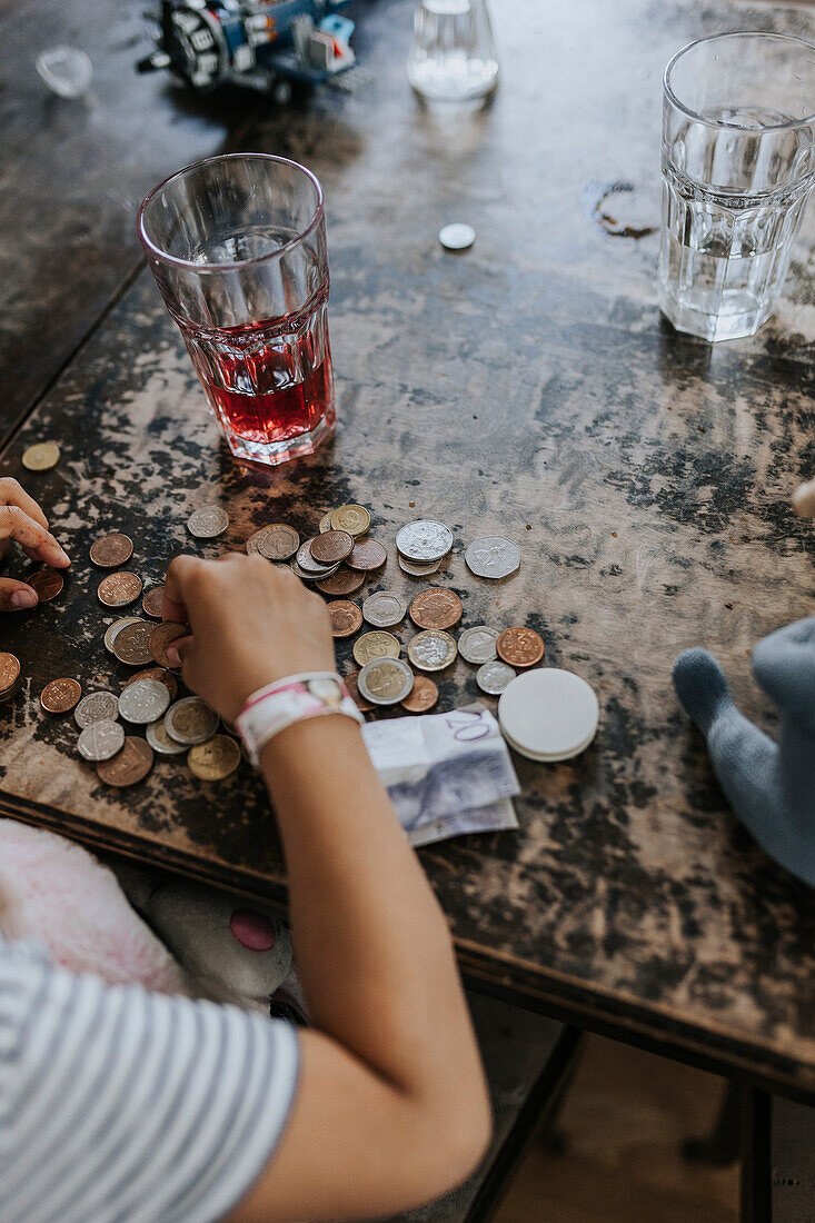 Kind zählt Münzen auf dem Tisch