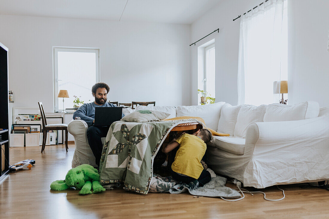 Mann arbeitet von zu Hause aus und kümmert sich um die Kinder