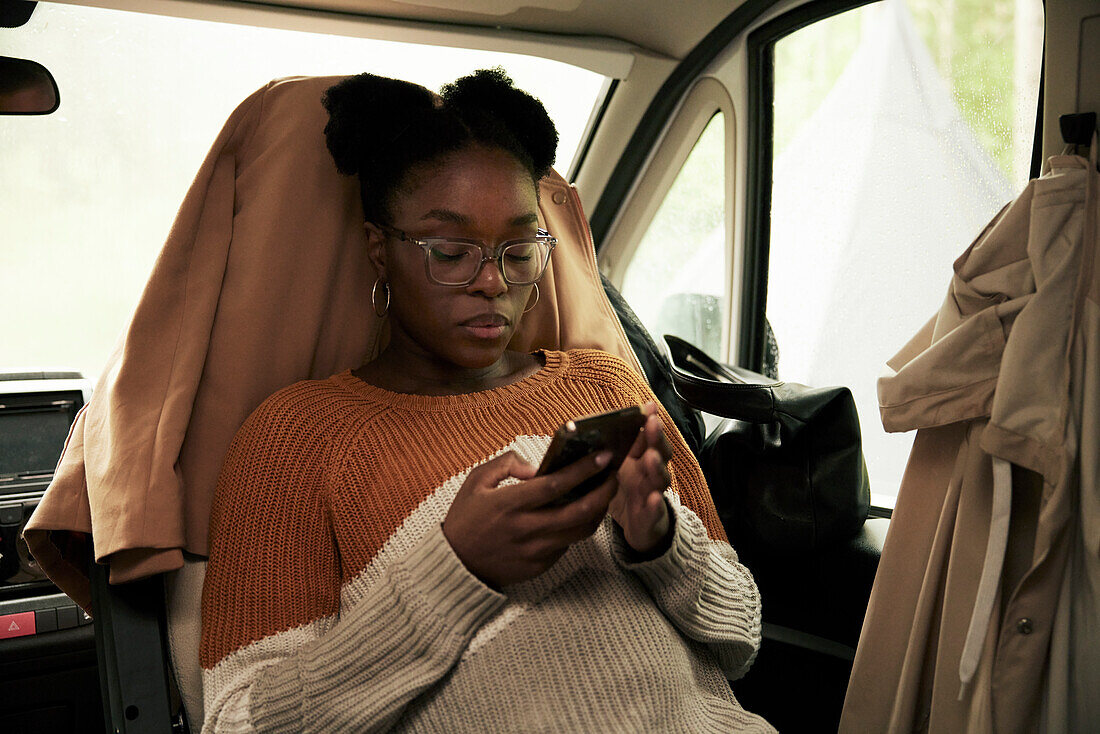Young woman using phone in camper van