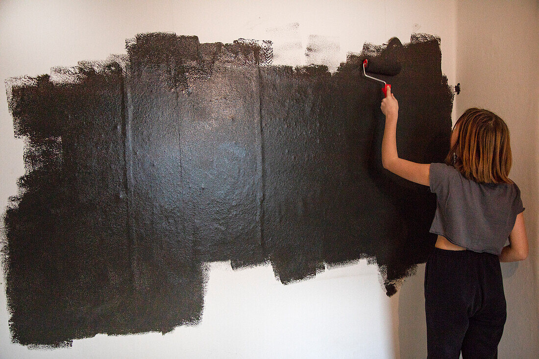 Frau malt Wand schwarz