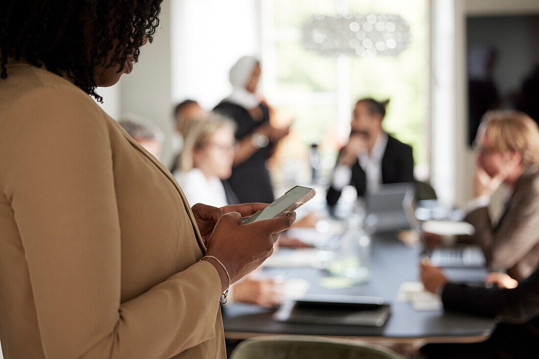 Woman using cell phone during business meeting