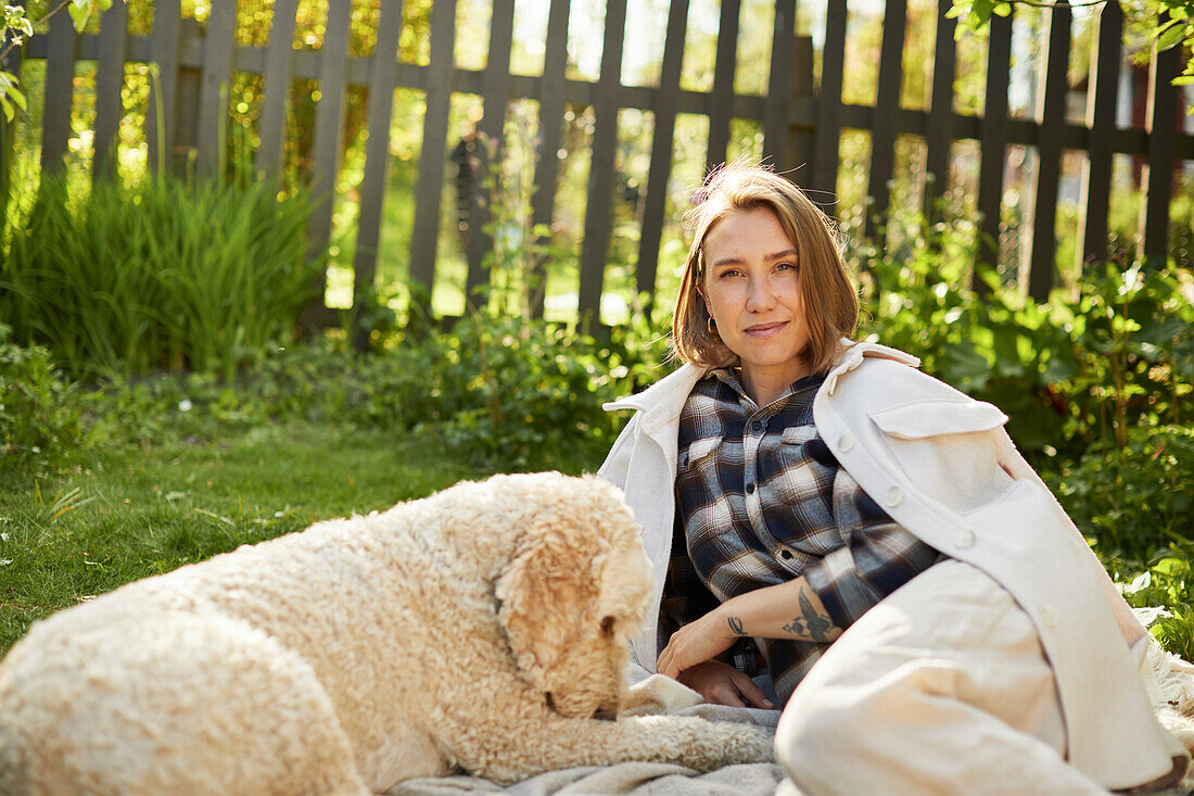 Frau entspannt mit Hund im Garten