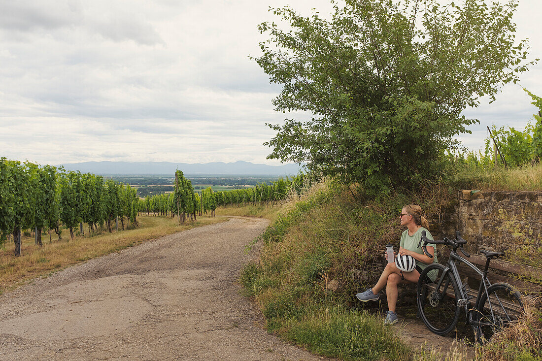 Female cyclist relaxing at vineyard