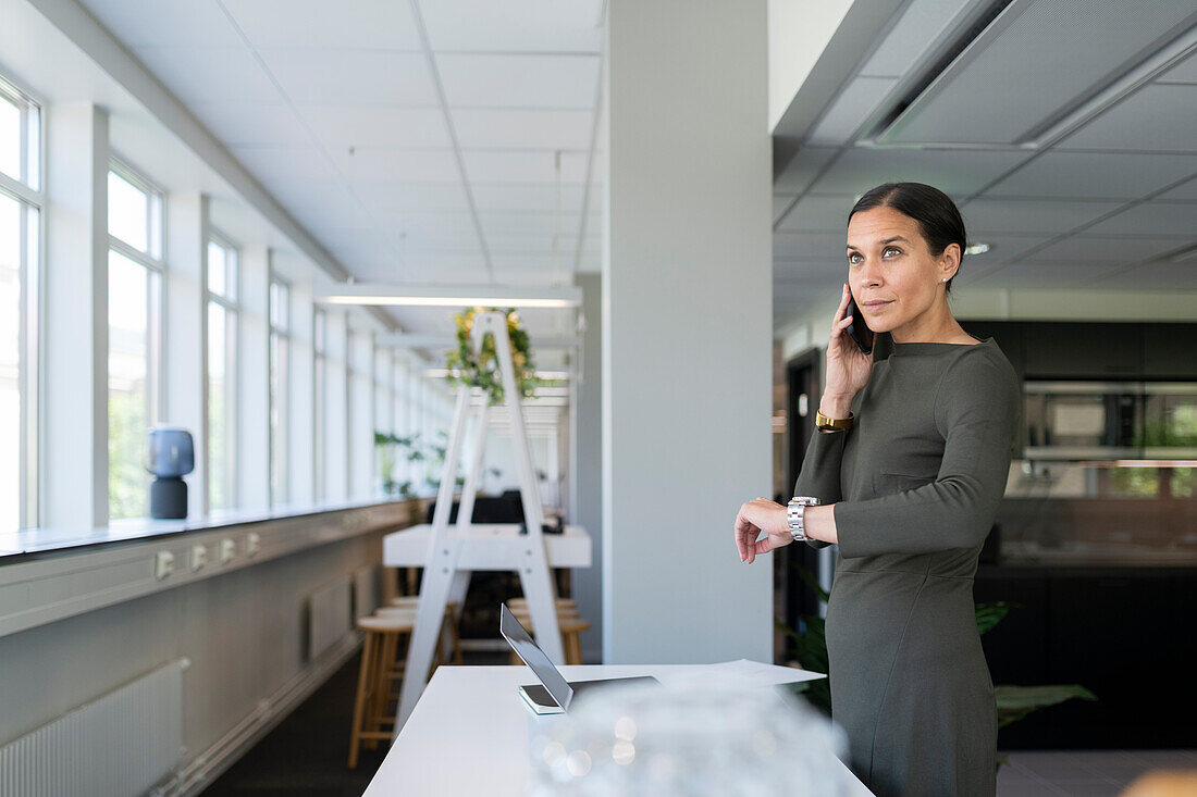 Frau im Büro telefoniert mit einem Handy