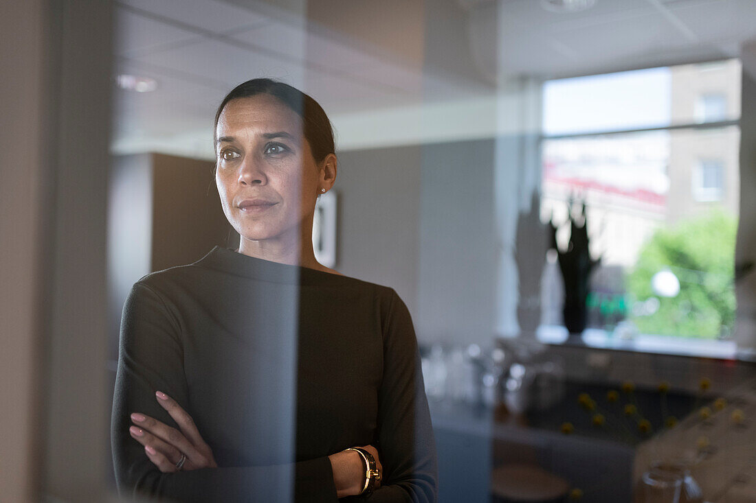 Geschäftsfrau im Büro schaut durch das Fenster