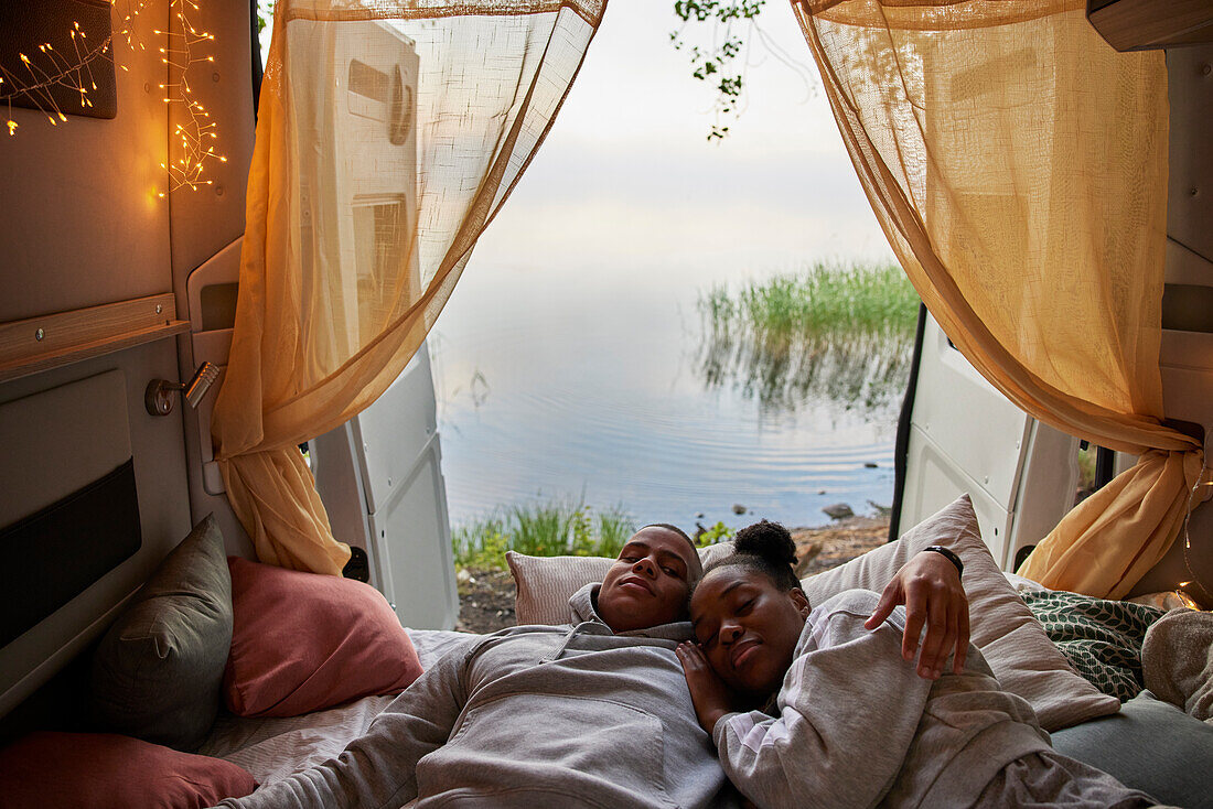 Young couple lying in bed in camper van