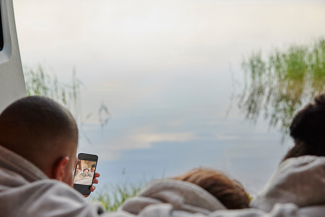 Friends lying in camper van and taking selfie