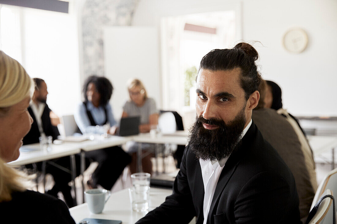 Businessman looking at camera during business meeting