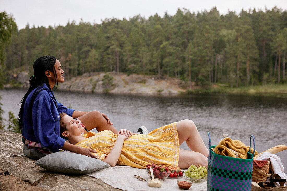 Female couple having picnic by river