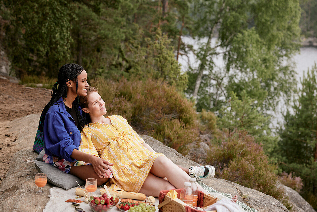 Weibliches Paar beim Picknick am Fluss