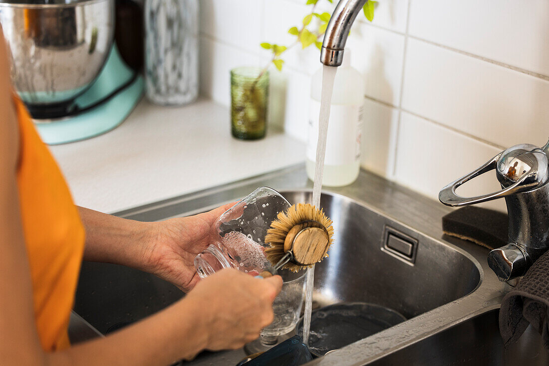 Woman washing dishes in kitchen sink