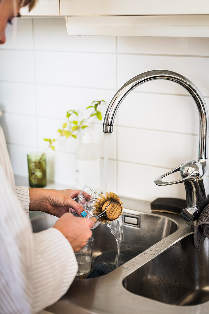 Woman washing dishes in kitchen sink