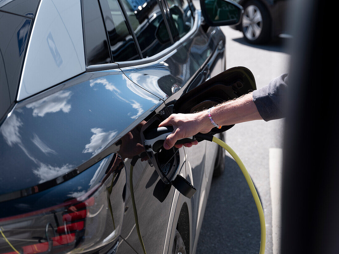 Frau lädt Elektroauto auf