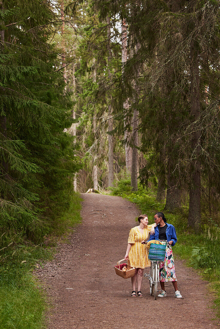 Weibliches Paar beim Spaziergang im Wald mit Fahrrad