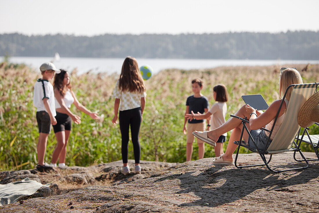 Mutter mit Kindern beim Entspannen am See