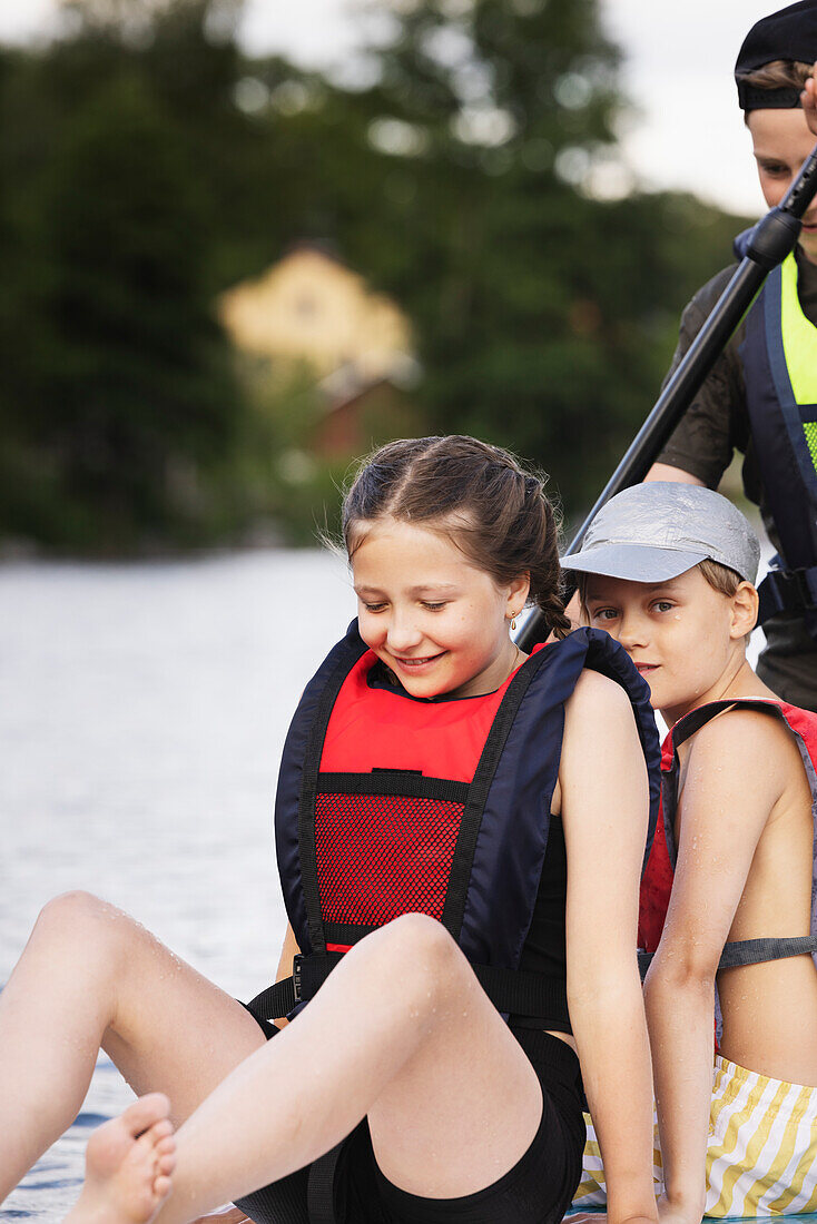 Siblings paddle boarding on lake