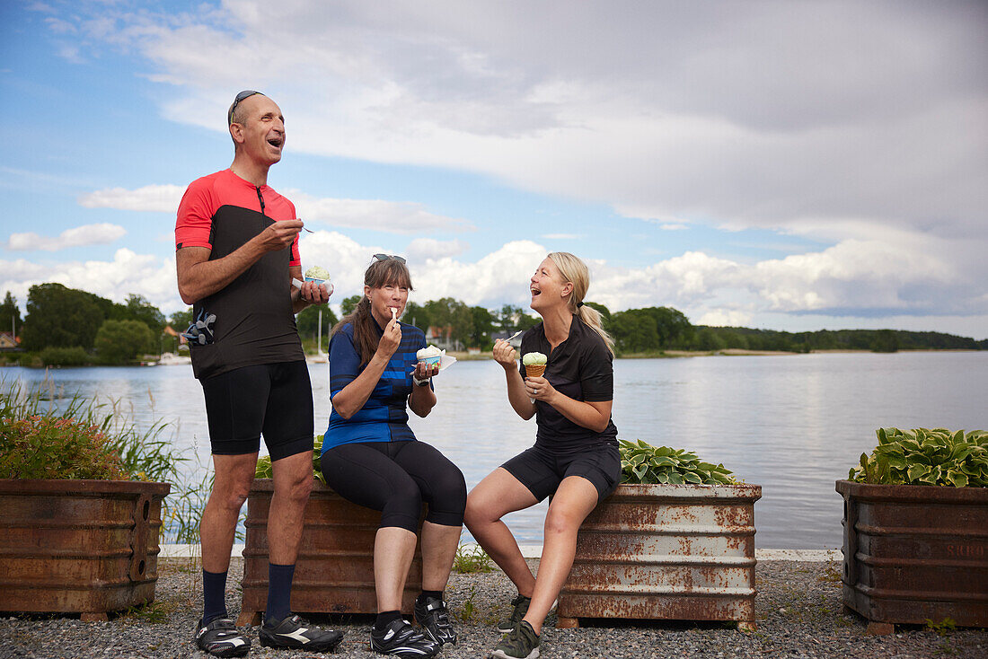 Glückliche Freunde beim Eisessen am Wasser