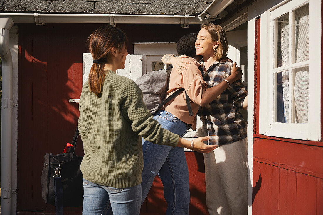 Smiling friends standing in front of wooden house