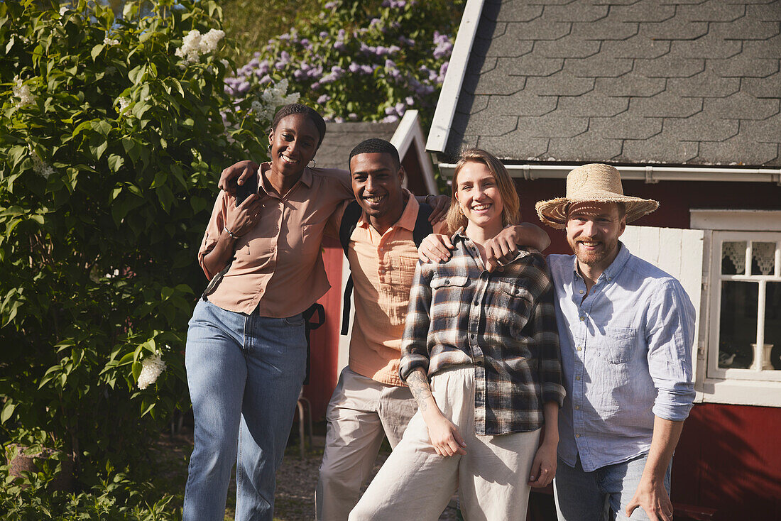 Smiling friends standing in front of wooden house