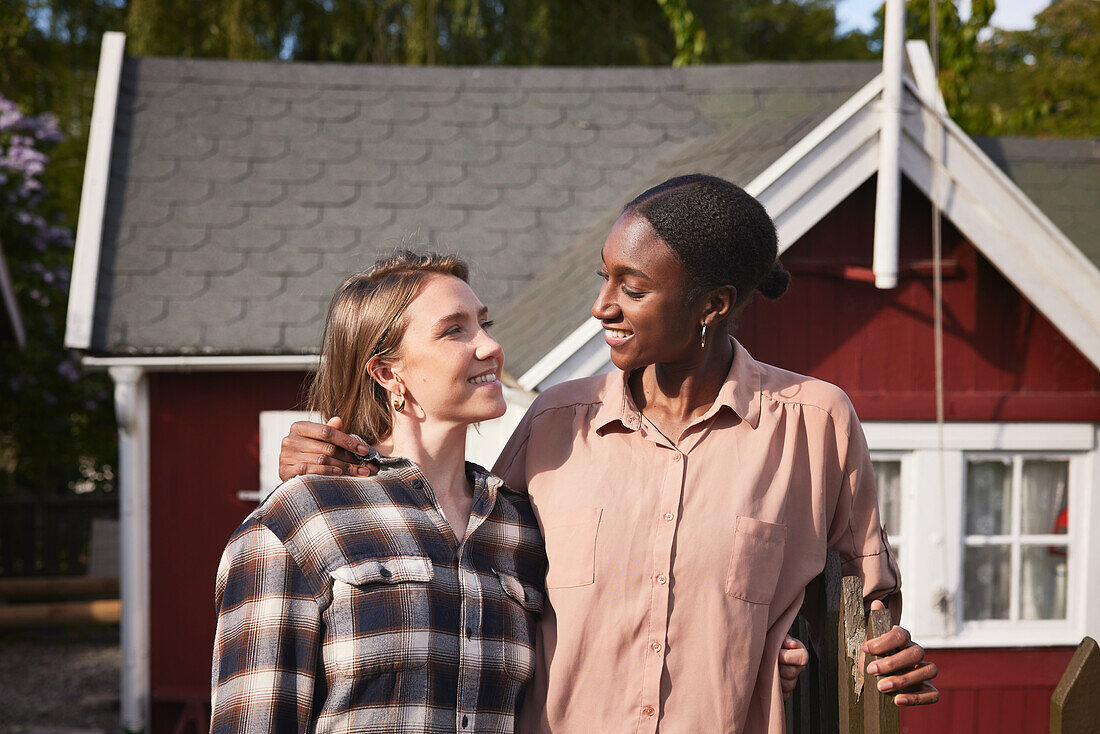 Smiling women standing in front of house