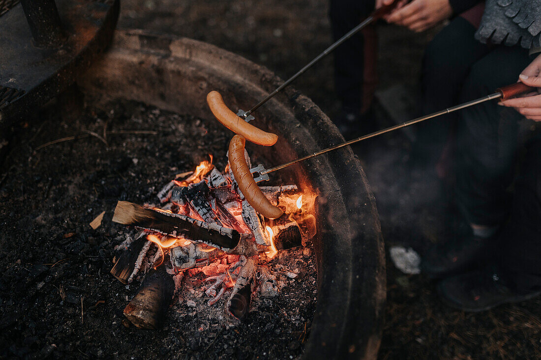 Grilling sausages above fire