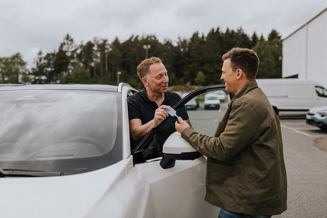 Autoverkäufer gibt dem Kunden die Autoschlüssel